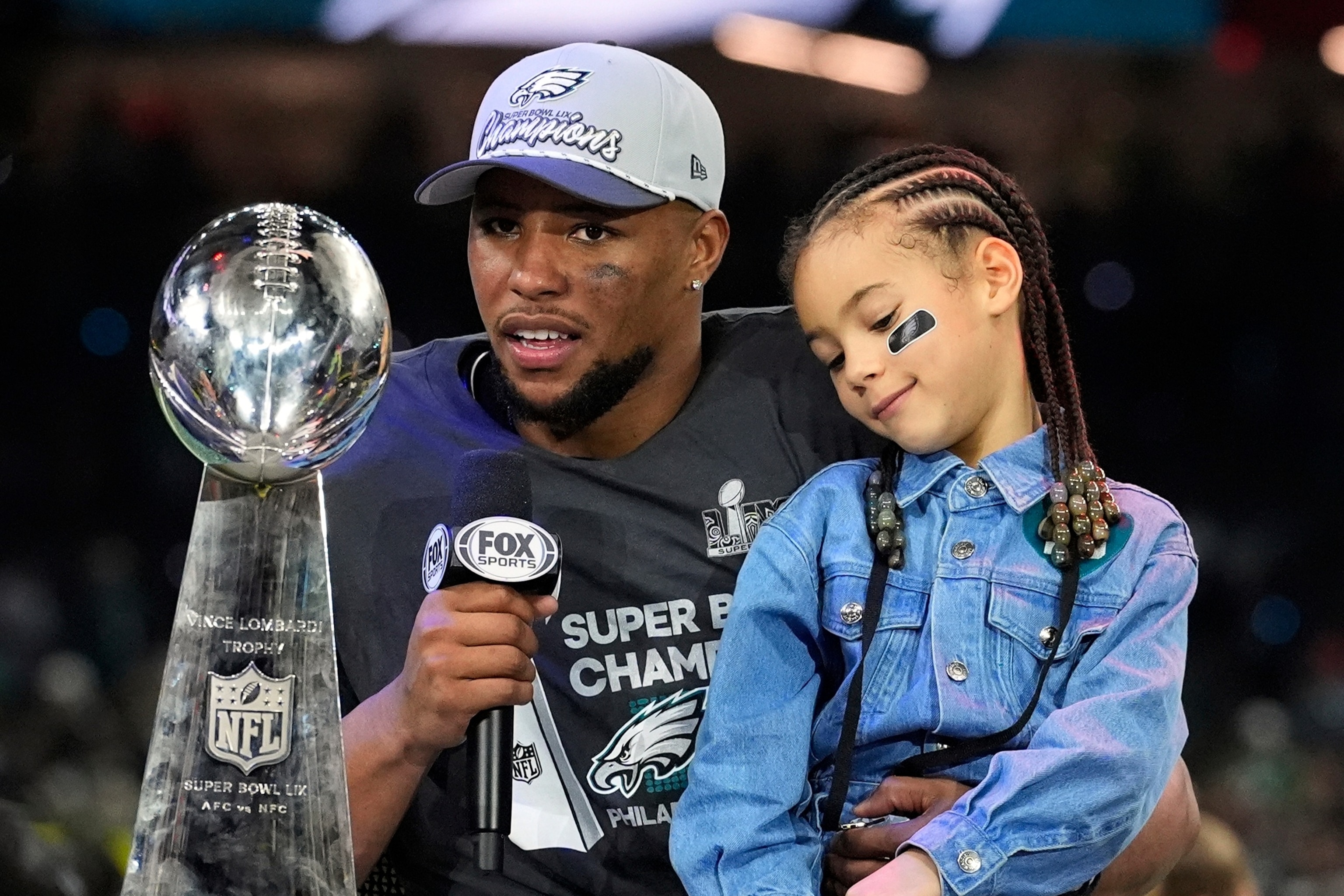 PHOTO: Philadelphia Eagles running back Saquon Barkley holds his daughter Jada while being interviewed after the NFL Super Bowl 59 football game against the Kansas City Chiefs,  Feb. 9, 2025, in New Orleans.